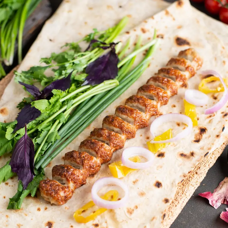Chicken kebab on lavash with onion and herbs