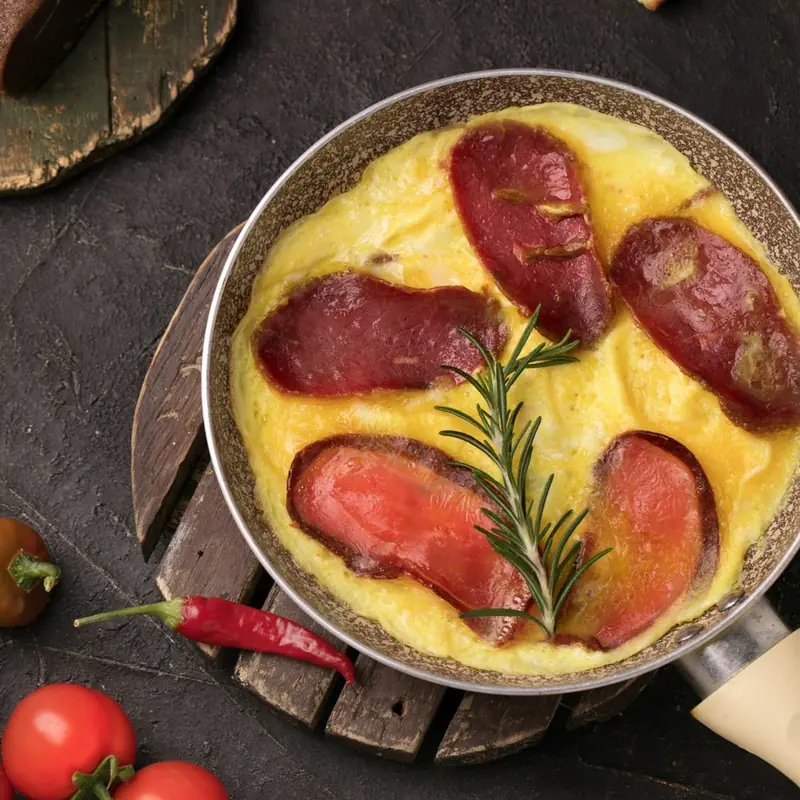 Omelette with basturma and rosemary in a pan