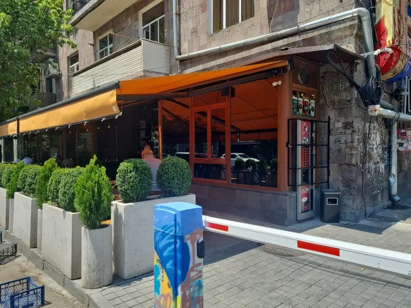 The corner facade with an orange awning over the street terrace
